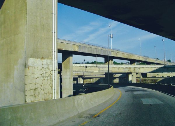 A cracked and discolored cement 4-level highway overpass under a blue sky.